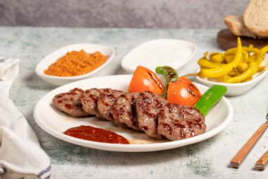 Izgara köfte. Domates, biber, aperatif ve özel sosla. Tabakta Türk köftesi