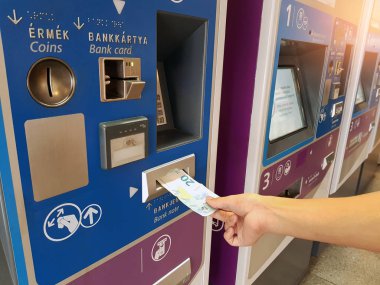Viyana, Avusturya - 22 Mayıs 2018: Avro banknotu taşıyan ve Avusturya 'nın Viyana kentinde metro biletleri için otomatik otomat kullanan yolcu.