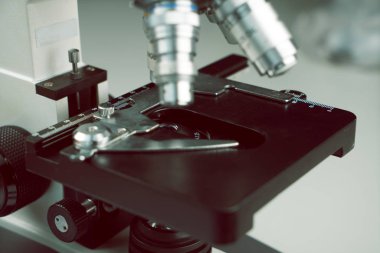 Laboratuvar araştırma masasındaki eski mikroskop, metal lens ve bilim ekipmanları ile yakın çekim. Öğrenciler için okul laboratuarı ve klasik mikroskop.