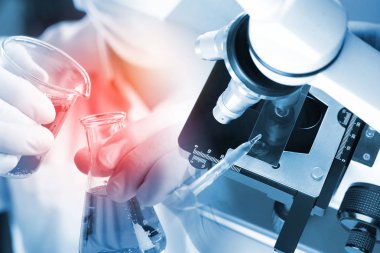 Genç Asyalı öğrenci ve beyaz mikroskop laboratuarda test için kırmızı sıvı ve damlatıcıyla. Bilim laboratuarında teknisyenlerin sürgülü camlara kırmızı su damlatması..
