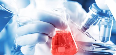 Kimyager çocuk biber bardağına mavi sıvı döküyor. Biyokimyasal deneyde kırmızı sıvıyla Erlenmeyer kimyasına. Suyu laboratuvarda karıştır.