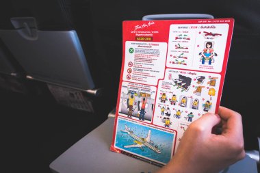 Bangkok, Tayland - 20 Kasım 2018: Asya adam uçuş kartı kurulu uçuş güvenlik talimatlarını okuyun. Yolcu ve yolcu güvenliği için gemide boş güvenlik talimatları.