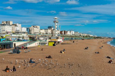 Brighton, İngiltere-1 Ekim,2018: Brighton Plajı'nın deniz, vitrin, hayat kurtaran kulesi ve arka planda sahilde güneşlenen insanların yer verdiği Brighton İskelesi'nin güzel manzarası. Şehrin popüler dönüm noktası.