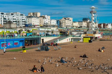 Brighton, İngiltere-1 Ekim,2018: Brighton Plajı'nın deniz, vitrin, hayat kurtaran kulesi ve arka planda sahilde güneşlenen insanların yer verdiği Brighton İskelesi'nin güzel manzarası. Şehrin popüler dönüm noktası.