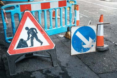 Kapalı yoldaki tabelasının altında ok işareti ve trafik konisi var. Uyarı sembolü yapım aşamasında, çalışma sürecinde..