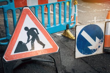 Kapalı yoldaki tabelasının altında ok işareti ve trafik konisi var. Uyarı sembolü yapım aşamasında, çalışma sürecinde..