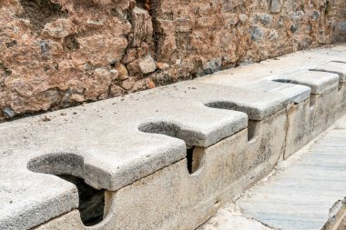 Türkiye 'nin Selcuk İzmir kentindeki Efes' teki görkemli antik harabelerde çok koltuklu tuvalet mermeri taşı ve kaya bulunuyor. Tarihi Antik Yunan tuvalet sistemi taşı.