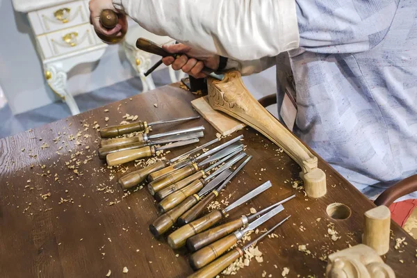 Furniture manufacturing with joiner tools, wood shavings and carpenter, working with chisel at the background.Horizontal photo with selective focus