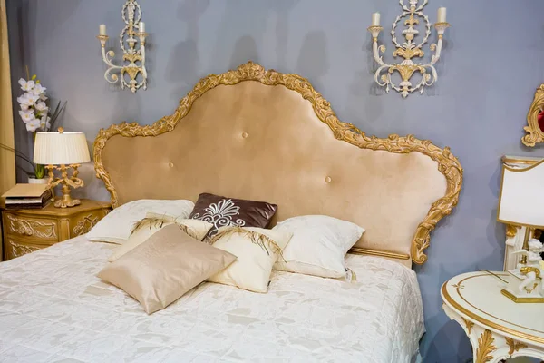 Luxury royal bedroom interior with bed and pillows and classic lighters on blue walls