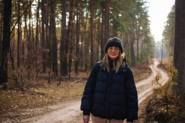 Genç gülümseyen kadın park alanında yürüyor.