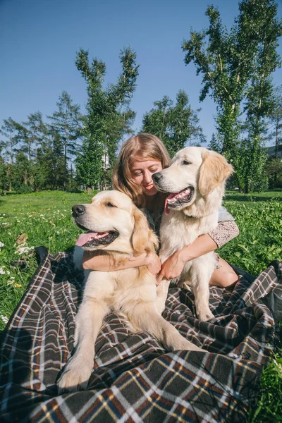 Девушка с двумя золотыми собаками-ретриверами в парке — стоковое фото