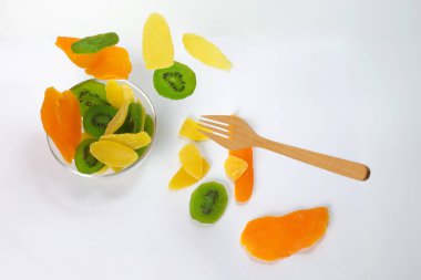 Kuru korunmuş yeşil kivi ananas olgun meyve renkli tatlı siyah mermer arduvaz arka plan cam kase üzerinde yükseltilmiş sarkık yüzen uçan dilim. 