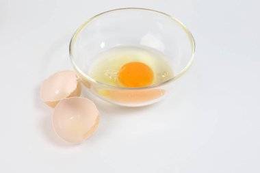 Çiğ yumurta sarısı ve beyaz sıvı saydam cam kase yumurta kabuğu beyaz arka plan 