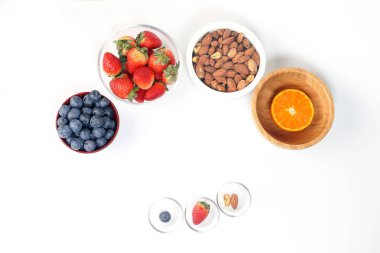Yaban mersini çilek bitki baharat badem kaşu fındık mandalina kase beyaz arka plan üzerinde 