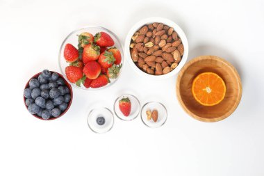 Yaban mersini çilek bitki baharat badem kaşu fındık mandalina kase beyaz arka plan üzerinde 
