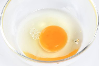 Beyaz arka plan çiğ yumurta sarısı ve beyaz sıvı saydam cam kase 