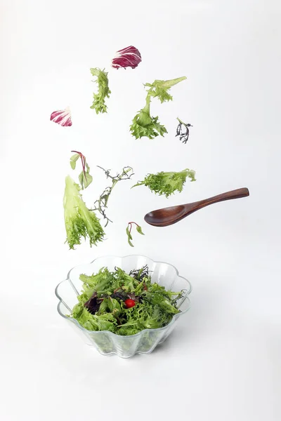 Mix leafy vegetable salad green purple lettuce glass bowl elevated flying dropping