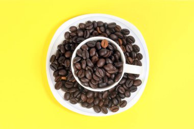 Sarı renk arka plan üzerinde kahve çekirdeği beyaz seramik fincan tabak 