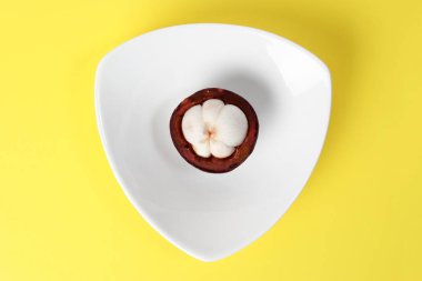 Mor mangosten meyve beyaz hart şekil plaka sarı arka plan üzerinde yarım mühürlü 