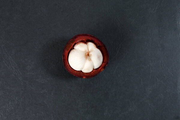 Purple mangosteen fruit pealed half on black background 