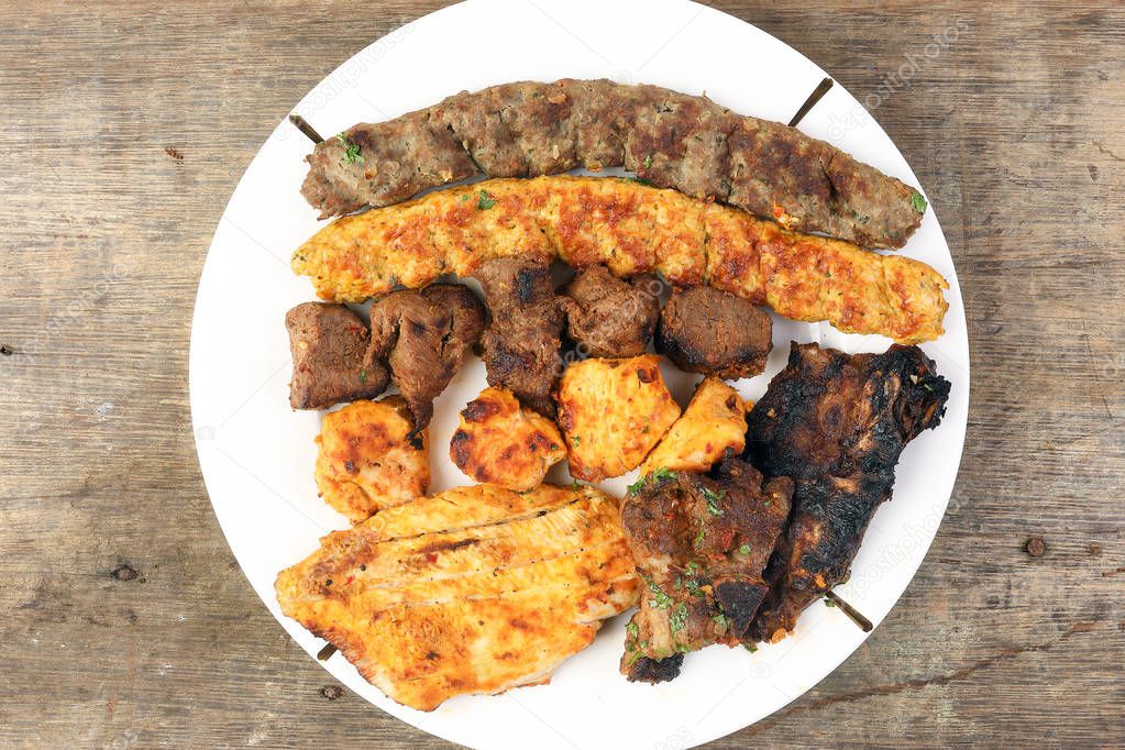 Mixed charcoal grilled platter chicken beef mutton goat meat shish kebab tawook middle east Arab wooden table 