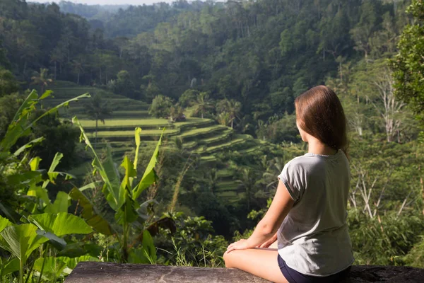 Mujer joven sentada en el banco y mirando la hermosa terraza de arroz en Bali, Indonesia —  Fotos de Stock