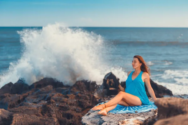 Женщина, сидящая на утесе над океаном — стоковое фото