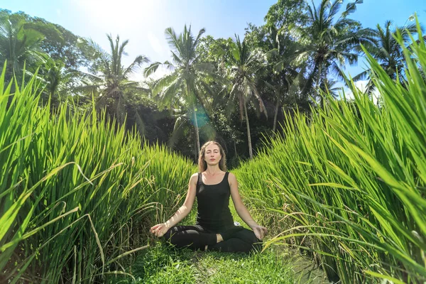 Young woman practicing yoga during luxury yoga retreat in Asia, Bali, meditation, relaxation, getting fit, enlightening, green grass jungle background,Terraced rice field in rice season in Bali