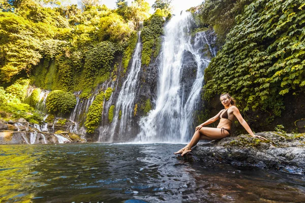 Genç seksi kadın ormanlarda şelale Banyumala bakıyor. Eko-turizm kavramı görüntü seyahat kız. Bali, Endonezya