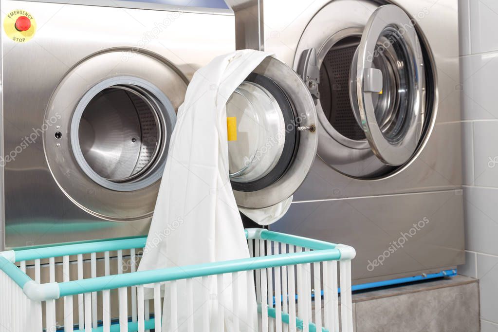 Washing machine overloaded with clothes and empty basket in laundry