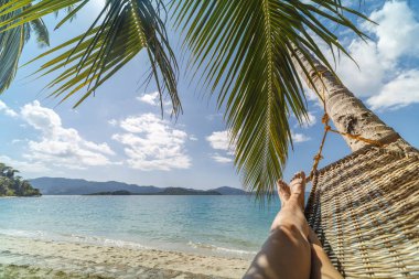 Açık deniz kenarında bir plajda bir hamakta yatan bir kadının seksi bacaklar