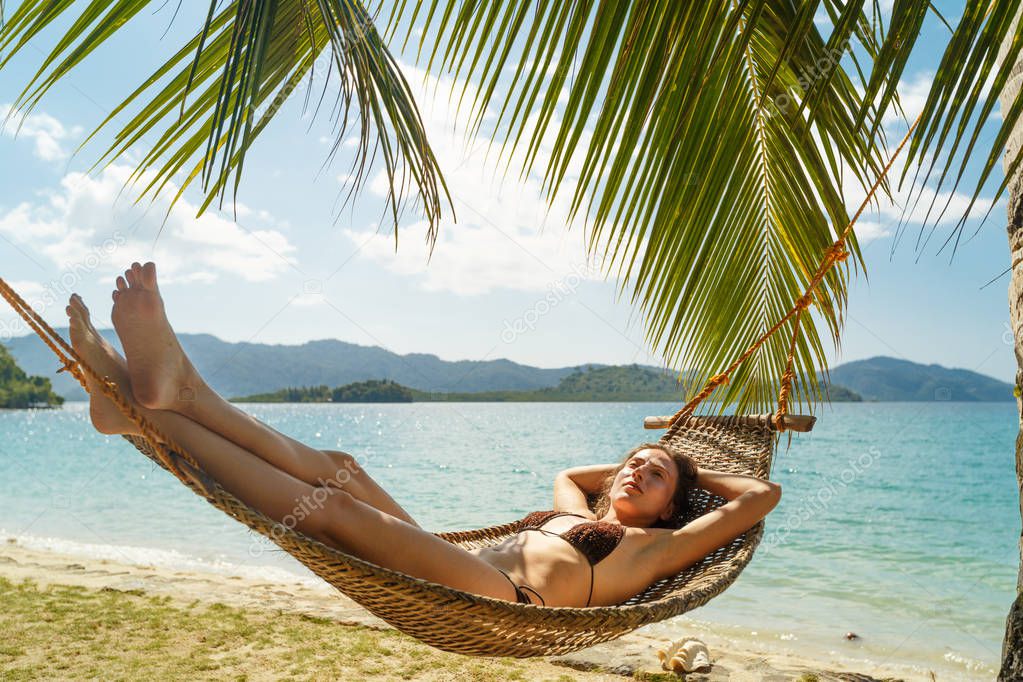 Summer vacations concept, Woman in swimsuit is relaxing in a hammock on a tropical beach El Nido on the Palawan island, Philippine