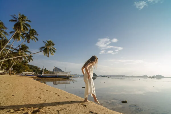 Mulher de pé na areia na praia de El Nido, degustando a temperatura da água molhando o dedo do pé enquanto em umas férias de verão. Viagens e ao ar livre estilo de vida . — Fotografia de Stock