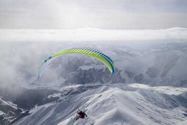 Güneşli kış aylarında kayak beldesi üzerinde karlı dağlarda Paragliding d