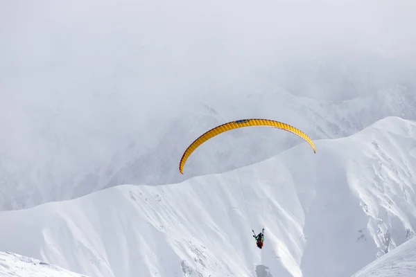 日当たりの良い冬のスキーリゾートの上の雪の山でパラグライダー — ストック写真