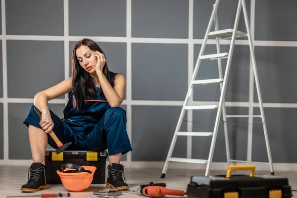 Üzgün kadın, yenileme daire için merdiven aletleri ile alet kutusunda oturur. Onarım ve ev iyileştirme. — Stok fotoğraf