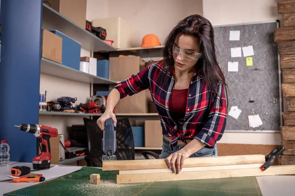 Home diy woman cutting plank of wood on workbench with saw renovating improving and decorating home — Stock Photo, Image