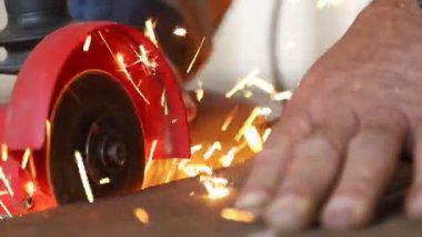İşçi öğütücüyle yakın plan metal borular kesiyor. Kıvılcımlar saçıyor.