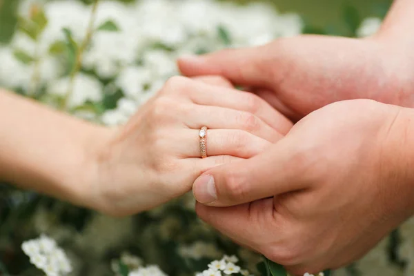 男は彼女の手を握ってフラワー ガーデンで彼のガール フレンドに婚約指輪を与えます 彼氏はフラワー ガーデンで婚約指輪と彼女のガール フレンドを驚かせた — ストック写真