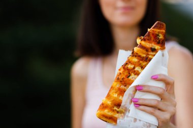 Kadının ellerini tutar parça ev yapımı pizza domates, sosis, salam ve peynir ile. Açık havada