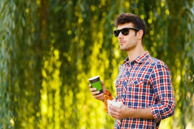 Genç adam yemek pizza, elinde kahve portresi. Mockup ürünler sunumları, logo ve metin için. Yaşam tarzı.