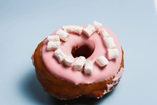 Pink donut with marshmallows on a blue background