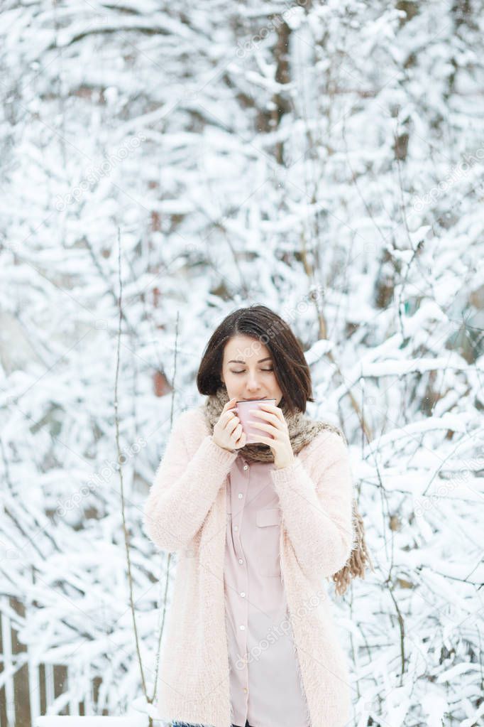 cute girl with a pink cup of coffee in the winter forest