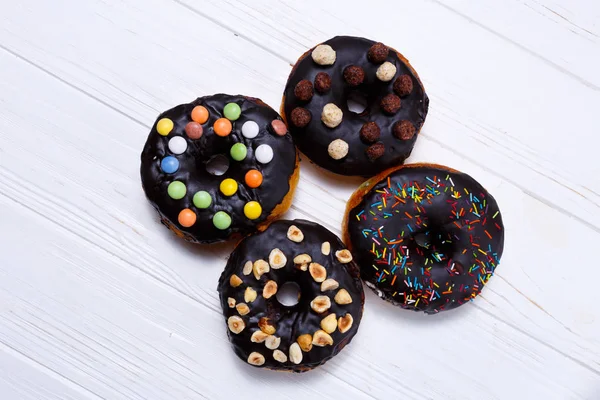 Delicious chocolate donuts with nuts over white background — Stock Photo, Image