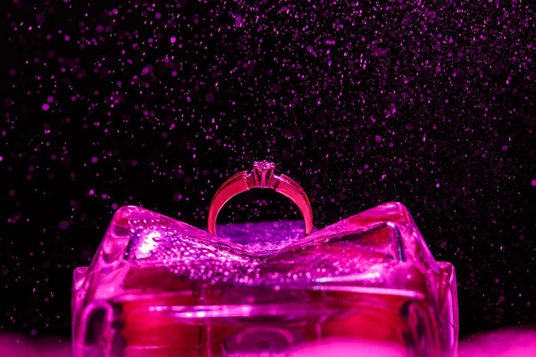 Anel de noivado em um suporte de vidro violeta com efeito de pequenos salpicos de água — Fotografia de Stock