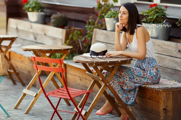Gözlük bir Cafe bir yaz terasında oturup bir şapka ile güzel bir gülümseyen mutlu Bayan portresi. Genç bir kız bir restoran masada oturuyor.