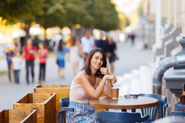 Bir yaz teras bir Cafe de oturup bir sıcak kahve ile güzel bir gülümseyen mutlu Bayan portresi. Genç bir kız oturuyor ve bir restoran masada kahve içme.