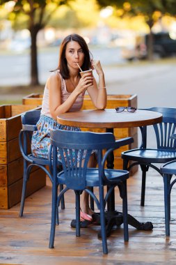 Bir yaz teras bir Cafe de oturup bir sıcak kahve ile güzel bir gülümseyen mutlu Bayan portresi. Genç bir kız oturuyor ve bir restoran masada kahve içme.