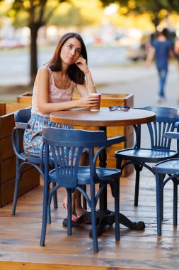 Bir yaz teras bir Cafe de oturup bir sıcak kahve ile güzel bir gülümseyen mutlu Bayan portresi. Genç bir kız oturuyor ve bir restoran masada kahve içme.