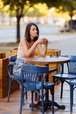 Bir yaz teras bir Cafe de oturup bir sıcak kahve ile güzel bir gülümseyen mutlu Bayan portresi. Genç bir kız oturuyor ve bir restoran masada kahve içme.